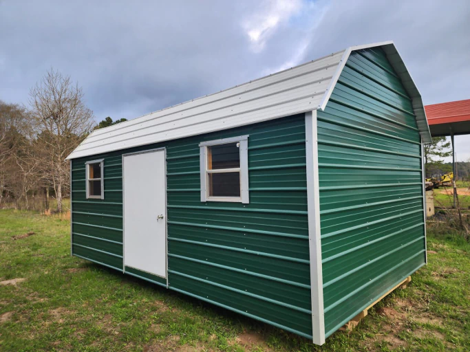 Green metal storage shed with a white gable-style roof